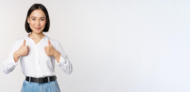 Image of beautiful adult asian woman showing thumbs up wearing formal office university clothing rec