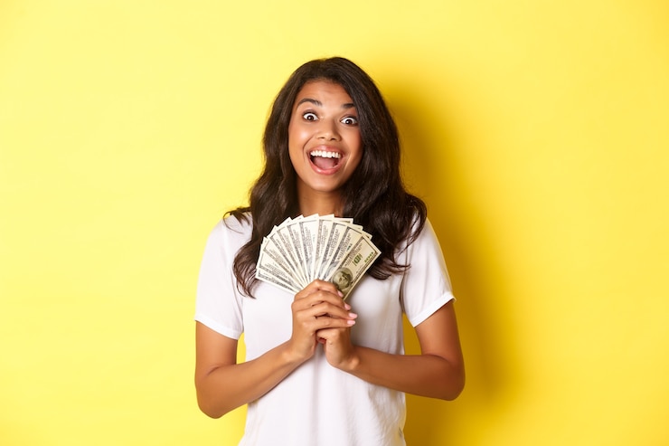 Free Photo image of beautiful excited africanamerican girl winning money prize and smiling holding cash