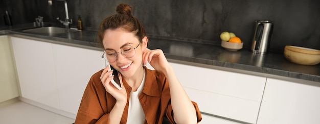 Free photo image of beautiful modern woman working from home studying in kitchen with laptop talking on