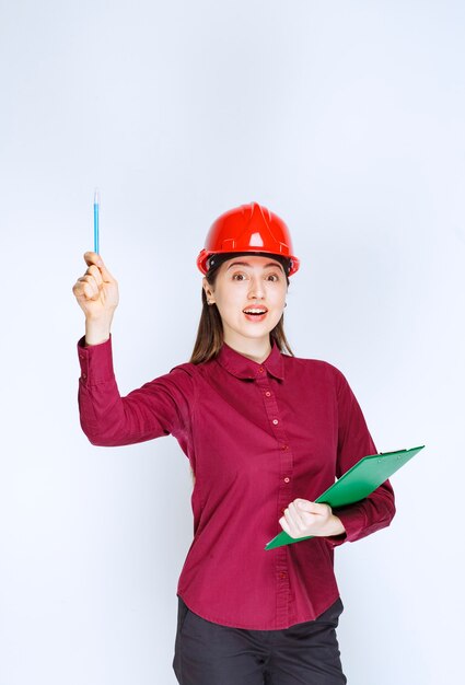 Image of beautiful woman in crash helmet holding pencil with folder. 