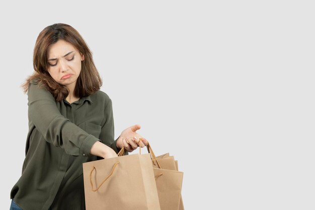 クラフトバッグから何かを脱いでいる美しい女性の画像。高品質の写真
