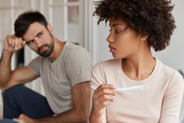 Free photo image of black african american wife sits back at edge of bed to her husband