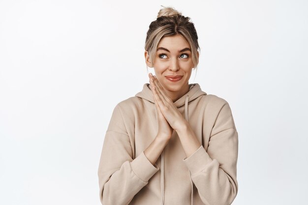 Image of blond woman rub hands and smiles thoughtful has interesting idea thinking of something has a plan standing over white background