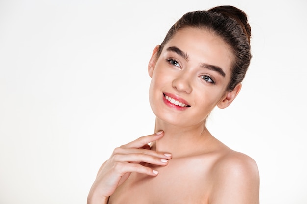 Image of brunette female with hair in bun and natural makeup smiling and looking aside