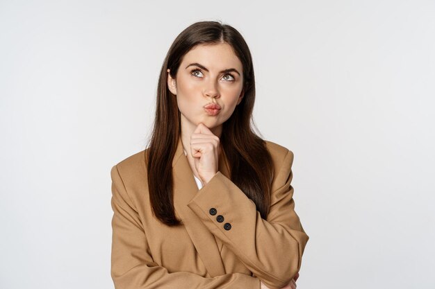 Image of businesswoman thinking corporate woman looking thoughtful making decision standing in brown...