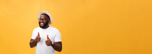 Free photo image of cheerful young african man standing and posing over yellow background with thumbs up lookin