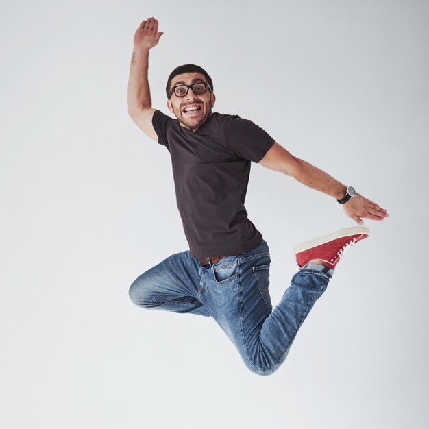 Образ веселый молодой человек случайный одет прыжки над белым