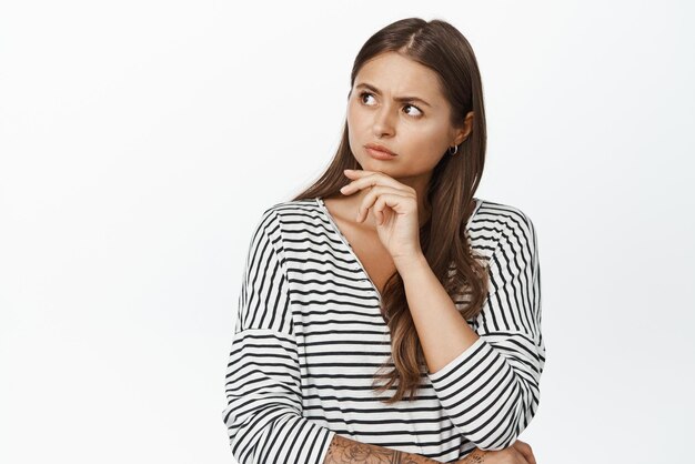 Image of concerned woman thinking looking at upper left logo with serious frowned face white background