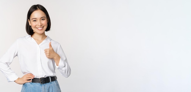 Immagine di una donna asiatica sicura di sé che mostra il pollice in su in segno di approvazione raccomandando come un buon posto dove stare