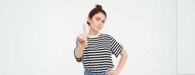 Free photo image of confident woman shows one finger taboo stop gesture disapprove smth gives warning stands