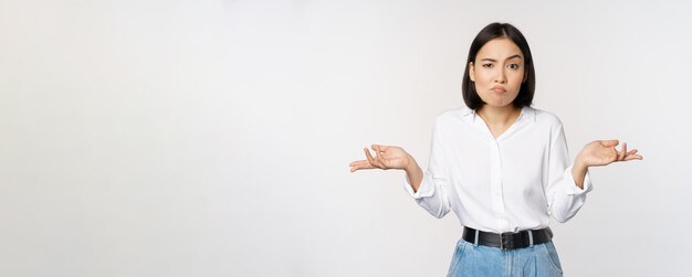 Изображение смущенной азиатской офис-менеджера офисной леди, пожимающей плечами и выглядящей невежественной, озадаченной на белом фоне