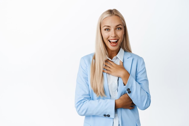 Image of corporate woman smiling looking surprised and flattered as if receiving smth standing pleased in suit over white background