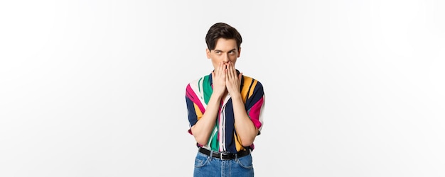 Image of cunning young man looking at upper left corner scheming something standing over white background