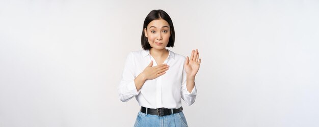 Image of cute young female office worker asian girl student raising hand up and put palm on chest na