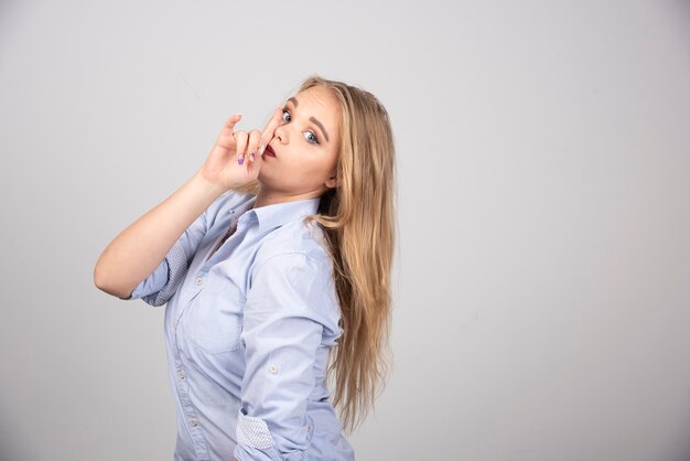 Image of a cute young woman model standing and doing silent sign