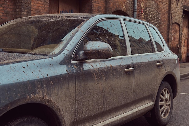 オフロード旅行後の汚れた車の画像。町の旧市街のレンガの壁に立っています。