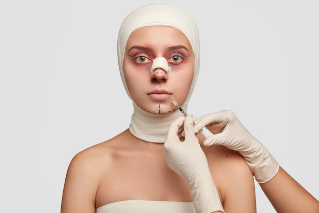 医師の美容師の画像は、患者に若返りの顔の注射を行い、唇の縮小手順は注射器を使用します。