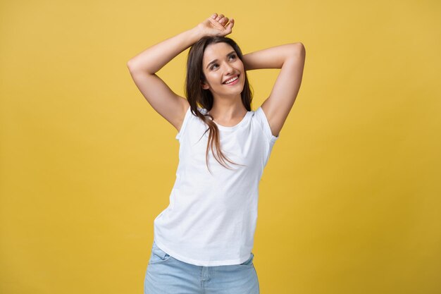 黄色の背景の上に孤立して立っている興奮した若い女性の画像カメラを見て