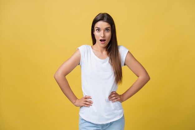 Image of excited young woman standing isolated over yellow background Looking camera