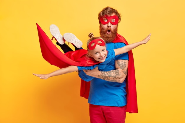 Image of ginger father and daughter dressed in superheroes