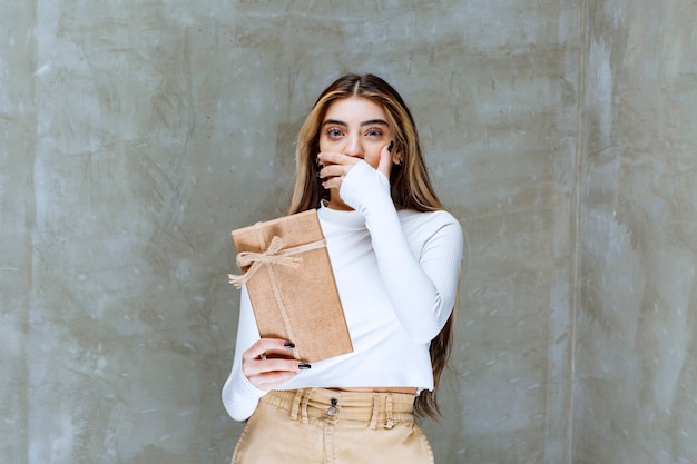 Image of a girl model holding a paper present over stone 
