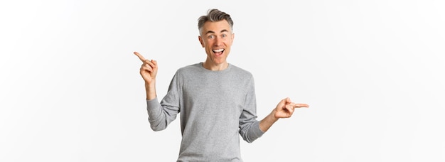 Изображение симпатичного мужчины средних лет в сером свитере, показывающего два варианта, указывающих пальцами в сторону.