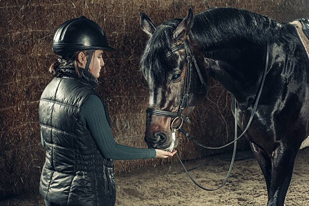 Image of happy female standing near on purebred horse