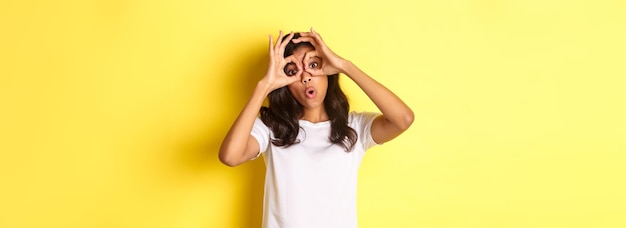 Free photo image of happy and funny africanamerican girl making finger glasses and looking through them at some