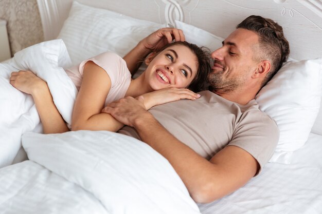 Image of Happy loving couple lying together on bed at home