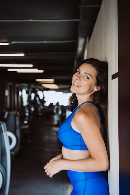 Immagine della ragazza felice di sport che controlla parete. guardando la fotocamera. riposo femminile dopo fitness.