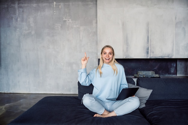 Free photo image of happy woman using silver laptop while sitting on sofa