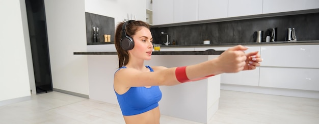 Foto gratuita immagine di una ragazza sportiva e laboriosa che fa esercizi di fitness a casa ascoltando musica in cuffia