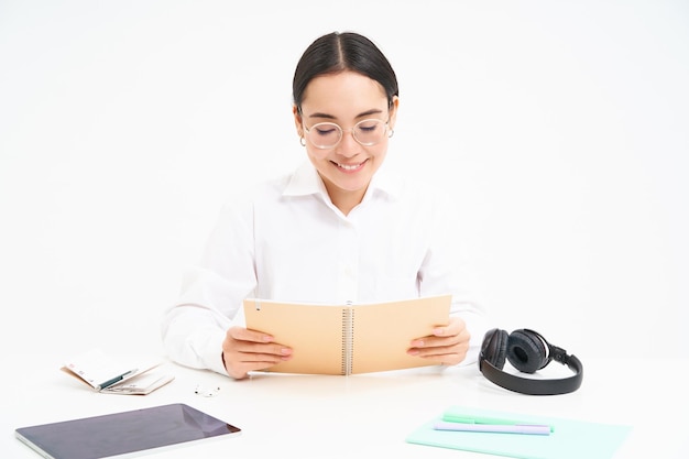 Free photo image of hardworking student asian woman in glasses studying holding notebook working on project iso