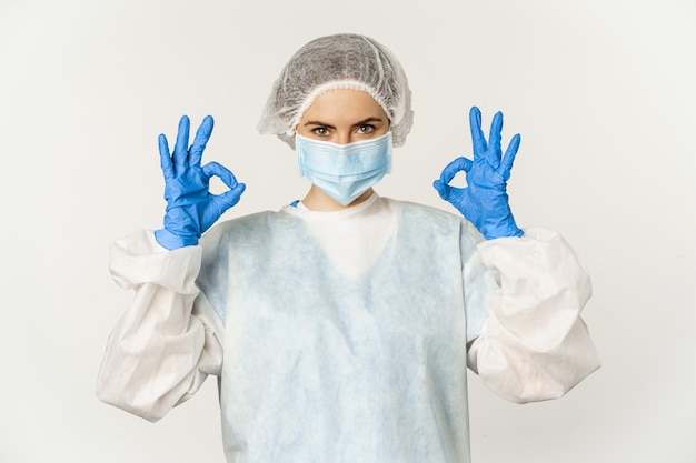 Free photo image of healthcare worker doctor in personal protective equipment from covid showing okay ok sign c...