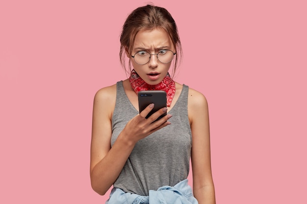 Image of indignant puzzled shocked woman stares at mobile phone