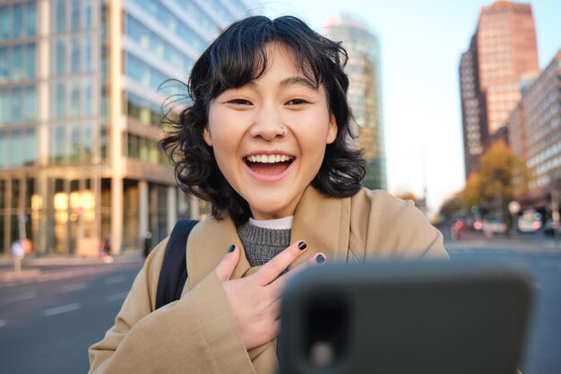 スマートフォンを使った韓国の女の子のビデオチャットの画像は、驚いて驚いた顔で彼女の電話を見る