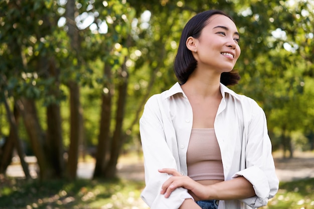 Image of korean girl walking in park smiling while having a mindful walk in woods