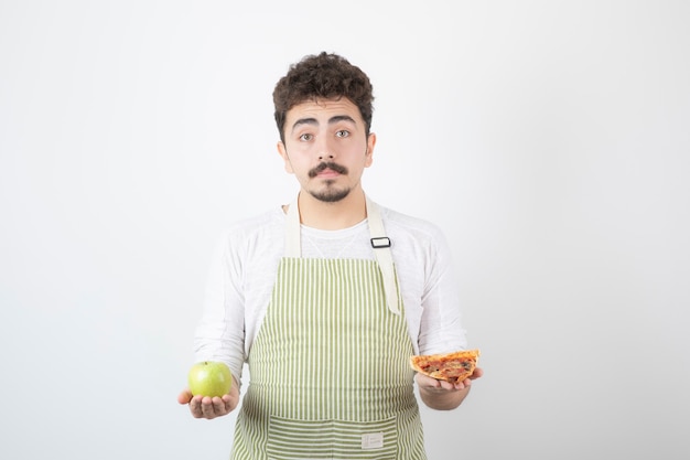 Immagine del cuoco maschio che tiene pizza e mela verde su bianco