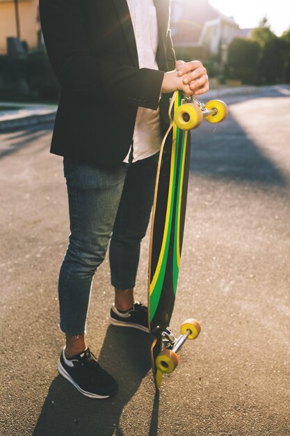 Image of a man with longboard going on road
