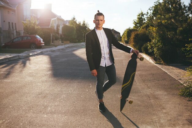 Image of a man with longboard going on road