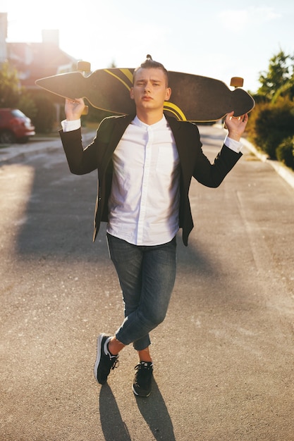 Image of a man with longboard going on road