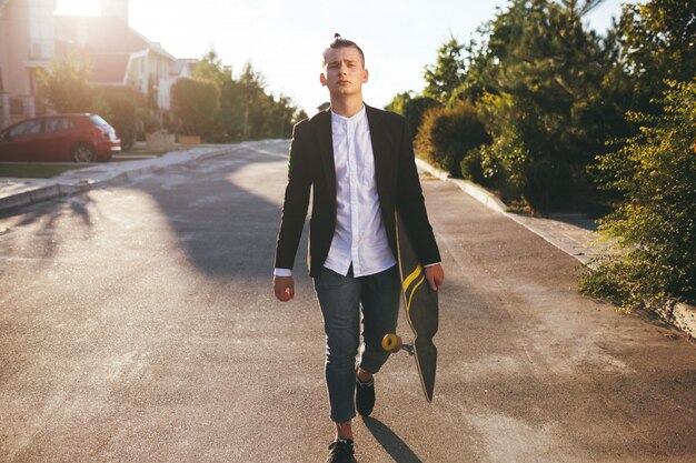 Image of a man with longboard going on road