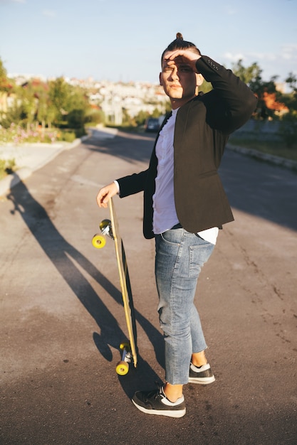 道路に行くロングボードを持つ男の画像