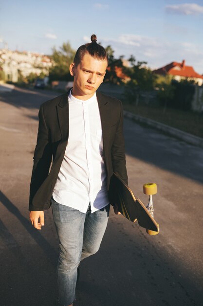 Image of a man with longboard going on road