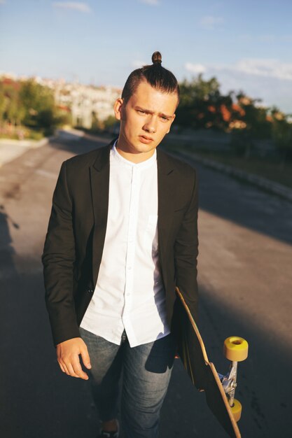 Image of a man with longboard going on road