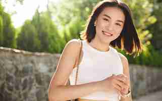 Free photo image of modern asian woman standing in park and smiling