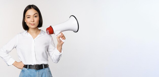 Free photo image of modern asian woman with megaphone making announcement white background