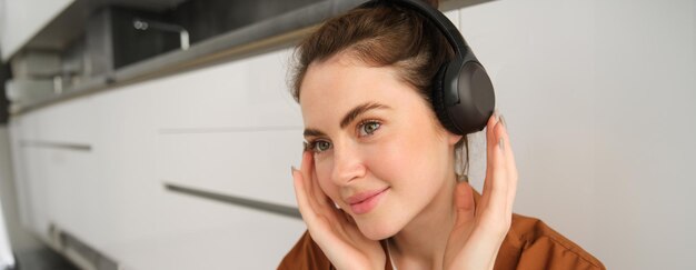 현대 여성의 이미지 아름다운 소녀는 음악을 듣는 것을 즐기고 앉아있는 검은 무선 헤드폰을 가지고 있습니다.