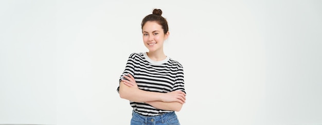 Бесплатное фото Изображение харизматичной молодой женщины в полосатой футболке и джинсах, выглядящей уверенно и счастливо, улыбающейся