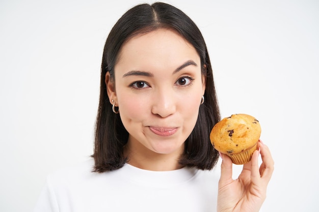 無料写真 カロリーの高いペストリーカップケーキを見せてjを食べることを禁じている若いアジア人女性の栄養士の画像